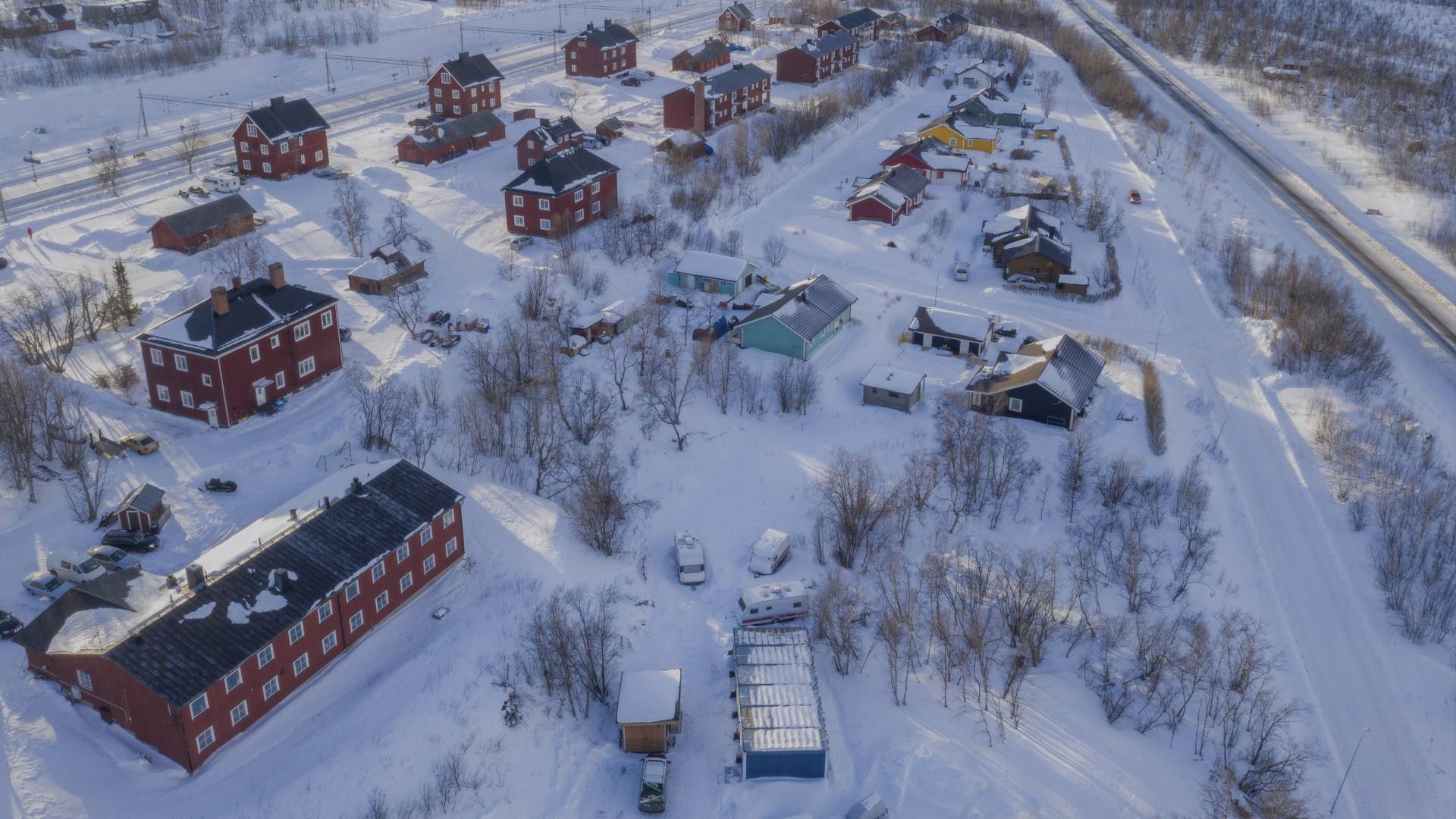 Vue aérienne d’Abisko enneigé en Laponie suédoise, avec le lac gelé Torneträsk et les montagnes du parc national en arrière-plan