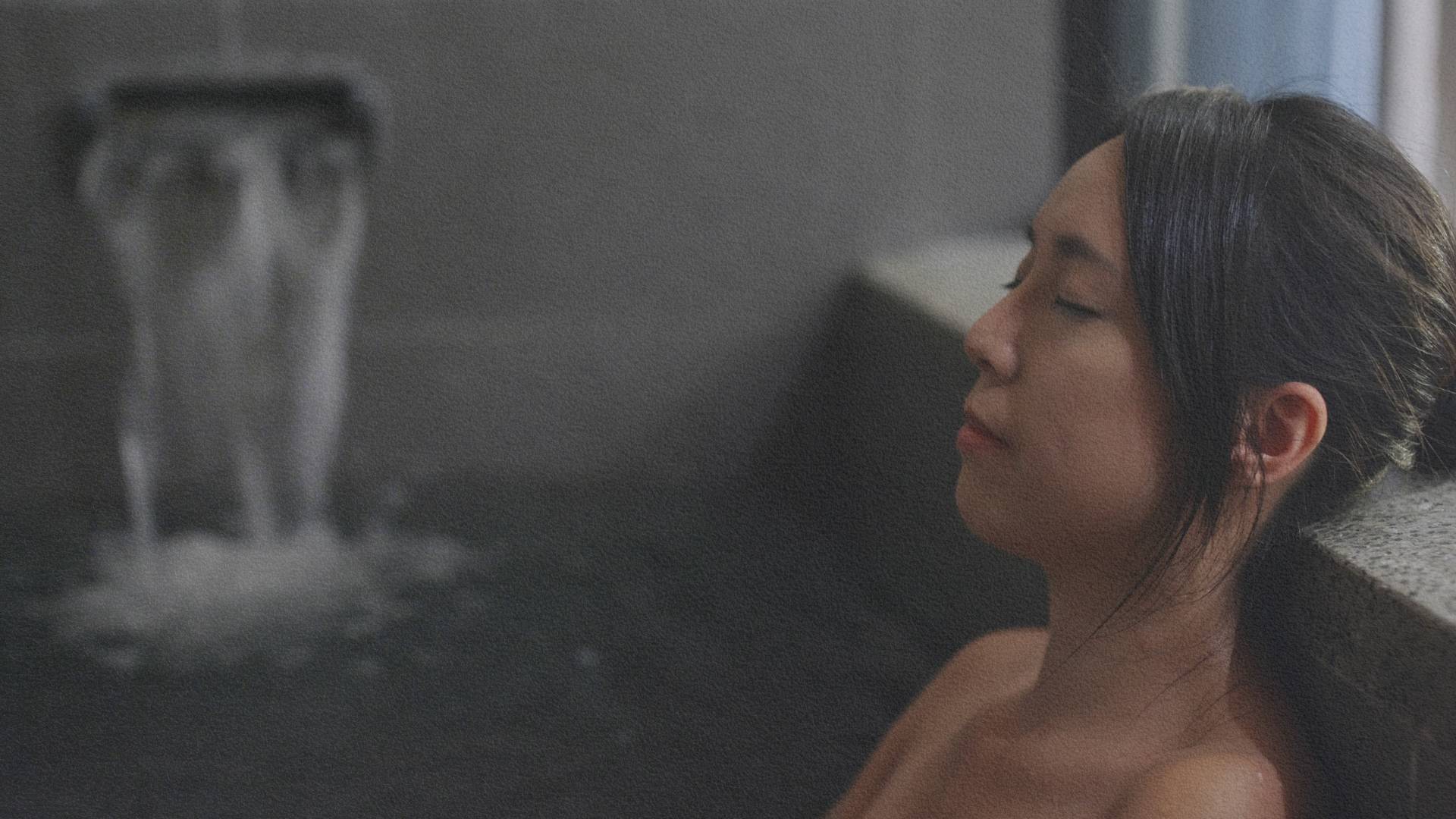 Femme dans un grand bain japonais, adossée et les yeux fermés – un moment de calme et de recentrage inspiré des rituels de purification traditionnels.