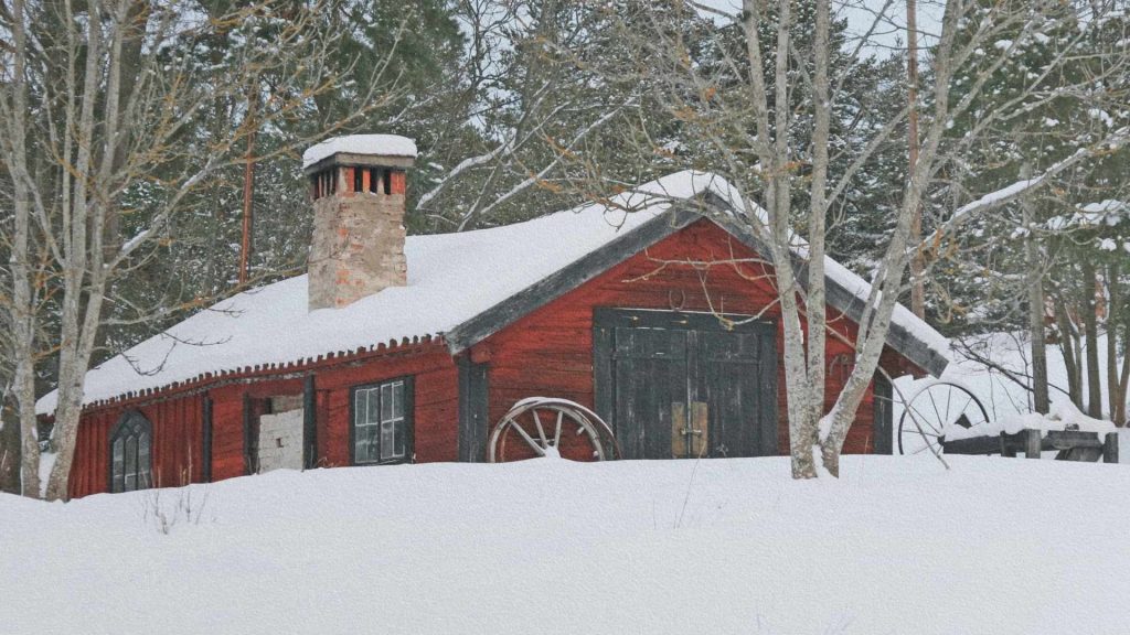 Maison rouge traditionnelle suédoise entourée de neige, forêt hivernale et lumière claire d’hiver.