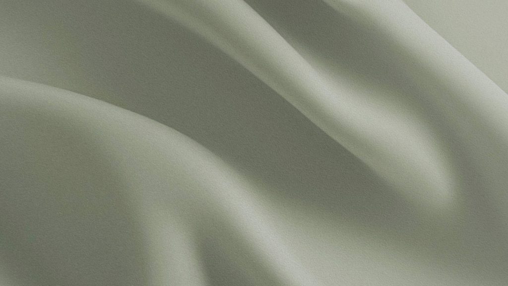 Tissu vert aux plis souples, surface textile lisse avec variations de lumière