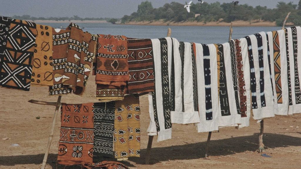 Bogolans traditionnels séchant à l’air libre, bandes de coton teintes et peintes à la boue aux motifs symboliques d’Afrique de l’Ouest