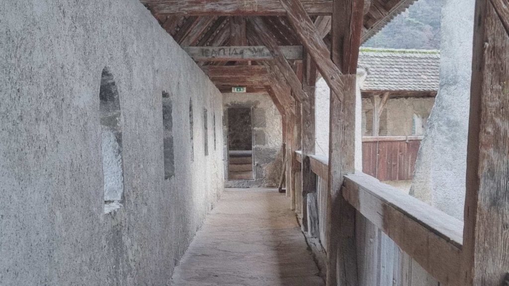 Chemin de ronde en bois du château d’Aigle avec murs en pierre et structure médiévale conservée révélant l’architecture défensive du lieu