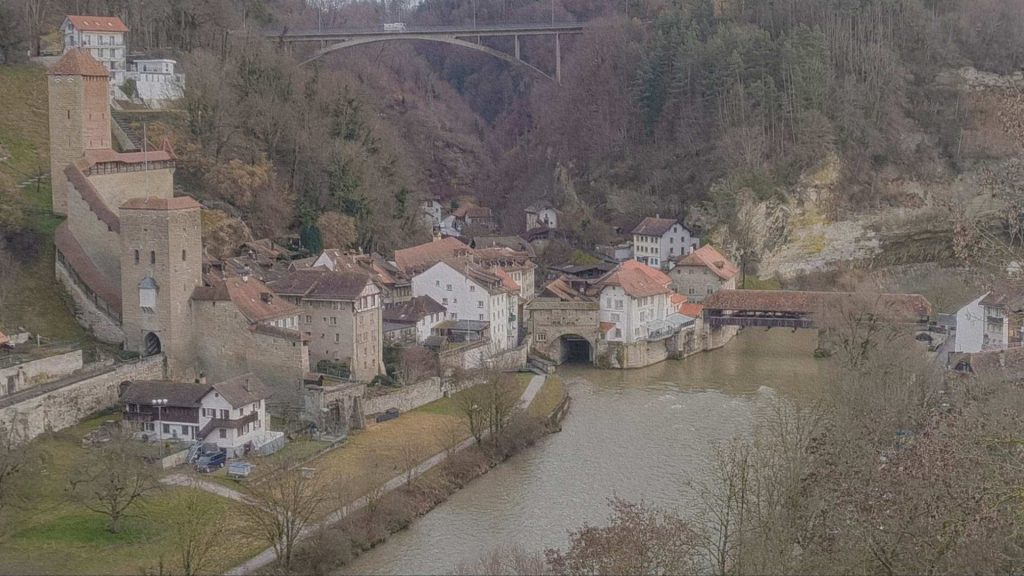 Vieille ville de Fribourg vue en hauteur avec la Sarine, le pont couvert en bois et les remparts médiévaux intégrés au relief