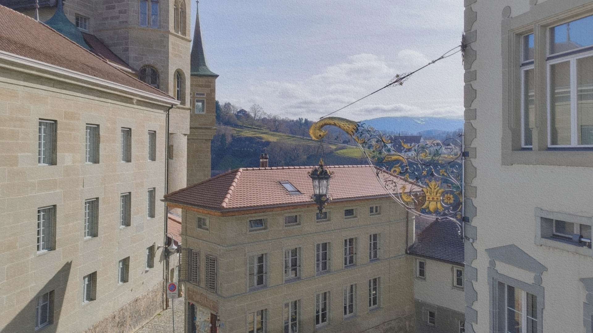 Façades anciennes et enseigne décorative dans la vieille ville de Fribourg avec collines visibles à l’arrière-plan