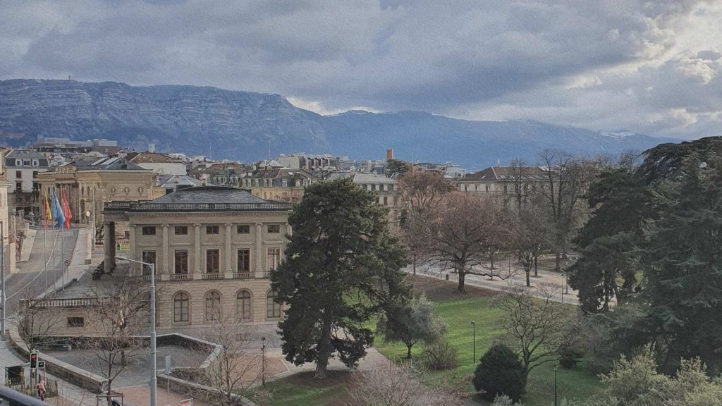 Vue sur le Grand Théâtre de Genève et le parc des Bastions, avec les bâtiments historiques et les montagnes en arrière-plan