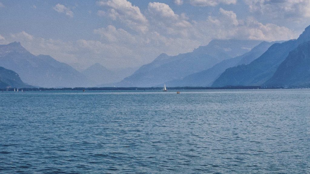 Vue du lac Léman avec voilier et montagnes alpines à l’horizon