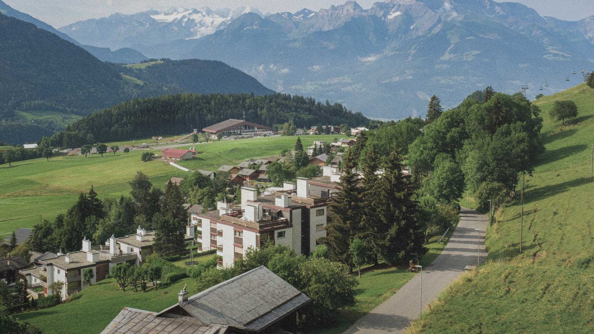 Sanatoriums et habitations de Leysin intégrés dans le paysage alpin avec prairies, forêts et montagnes suisses en arrière-plan