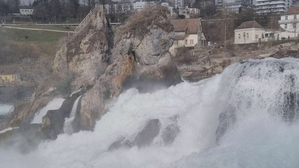 Chutes du Rhin en Suisse vues de près avec eau en cascade et rocher central montrant la puissance du fleuve dans son passage contraint