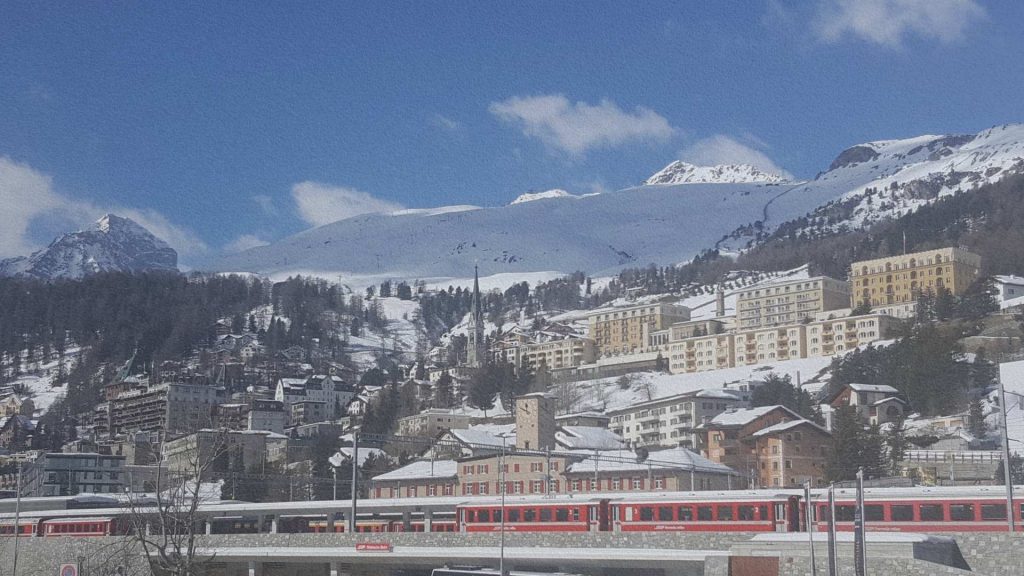 Saint-Moritz en hiver avec le train rouge et les hôtels surplombant la vallée de l’Engadine