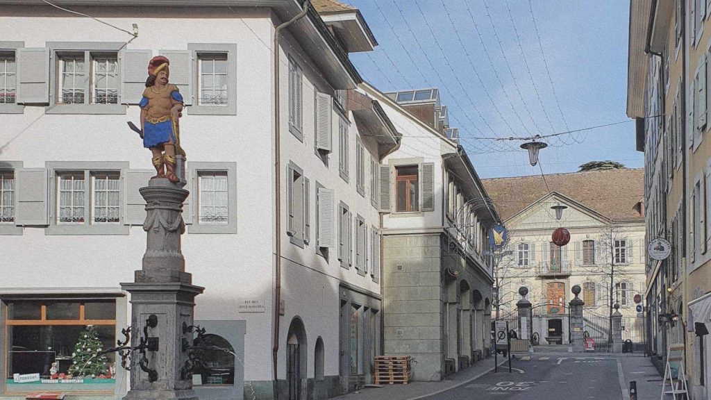Rue du centre historique de Vevey avec fontaine sculptée et bâtiments anciens