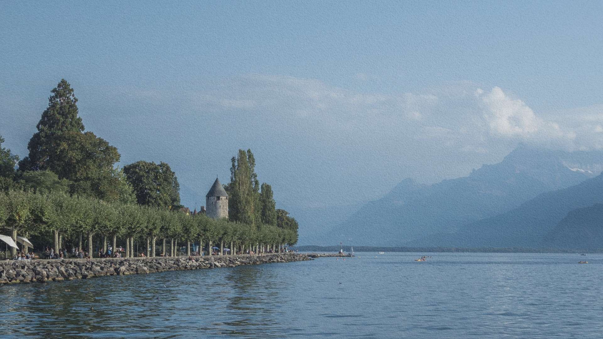 Promenade du lac Léman à Vevey avec tour médiévale, alignement d’arbres et Alpes en arrière-plan