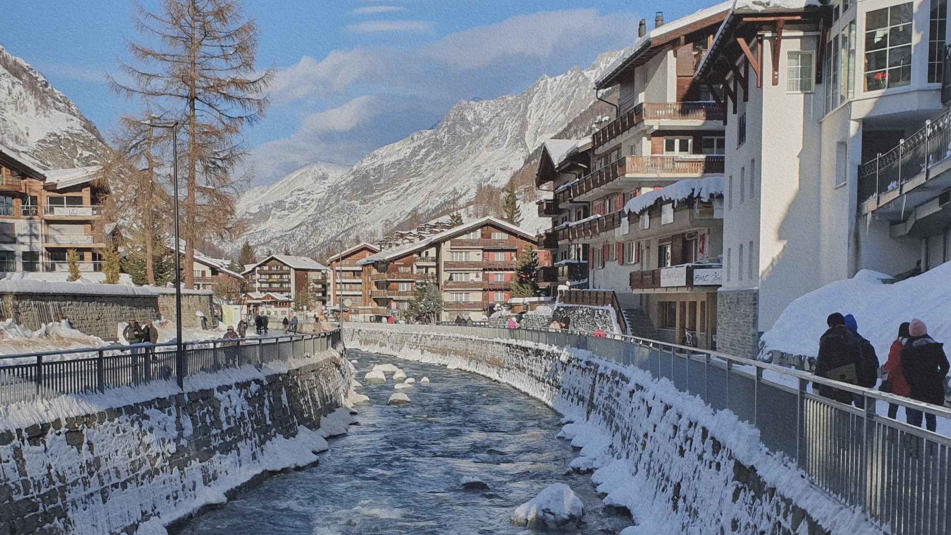 Village de Zermatt traversé par une rivière, entouré de chalets et de montagnes enneigées dans les Alpes suisses