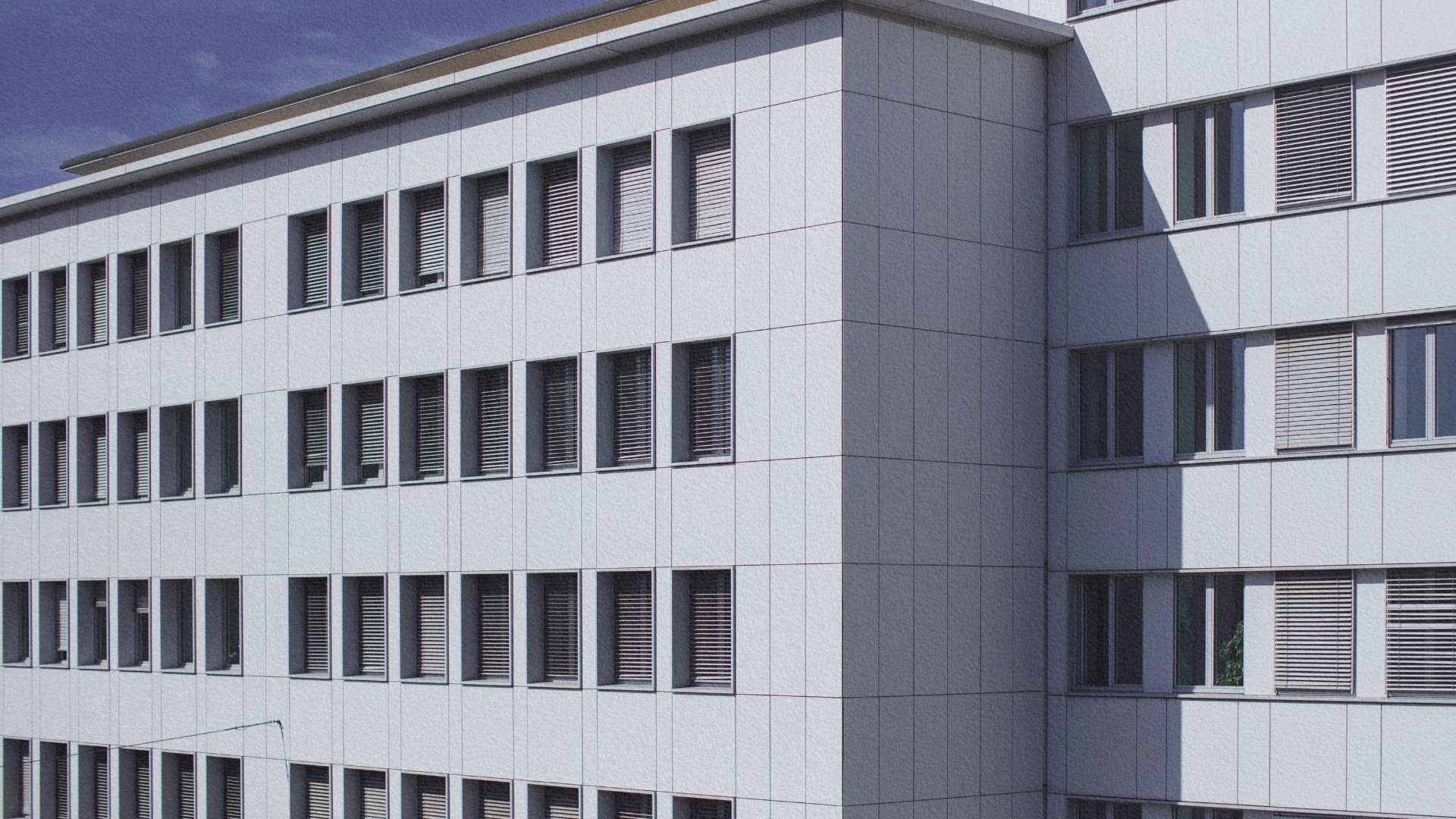 Façade moderne d’un bâtiment à Zurich en Suisse, composée de panneaux clairs et de rangées régulières de fenêtres avec stores.