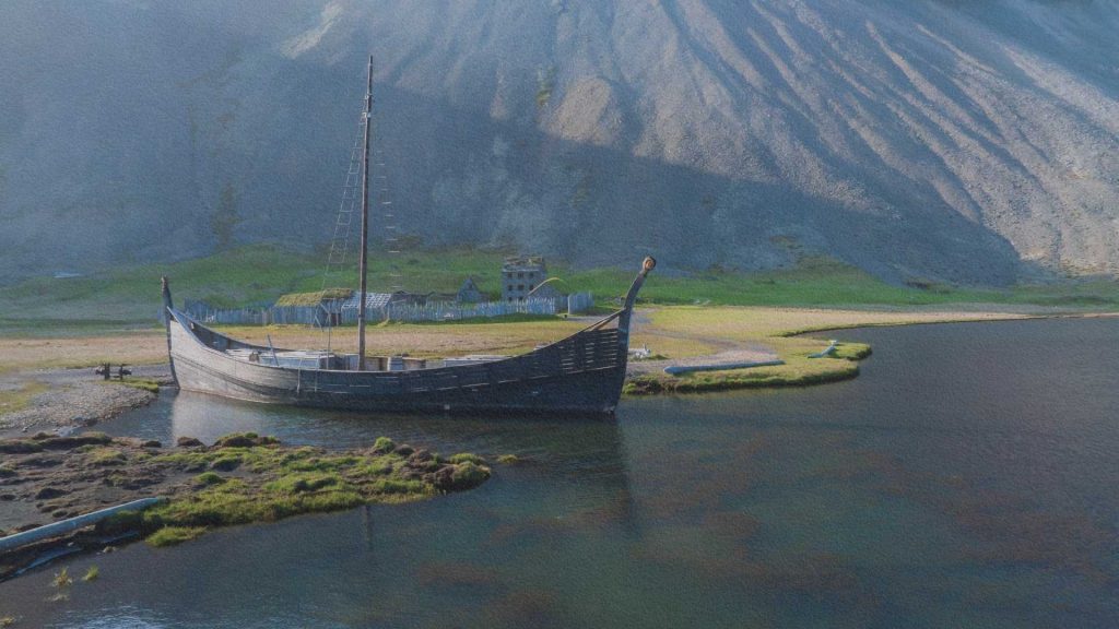 Reconstitution d'un drakkar viking sur une rive nordique, symbole des explorations scandinaves du Moyen Âge