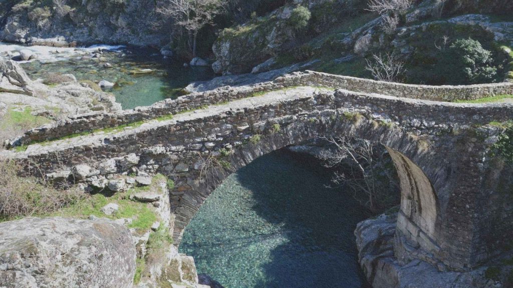 Pont de pierre médiéval franchissant une rivière de montagne dans le village d'Asco en Corse