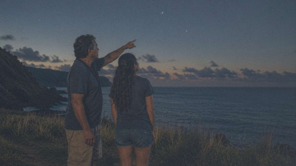 Un père montre une constellation à sa fille sur une falaise dominant le Pacifique, au crépuscule.