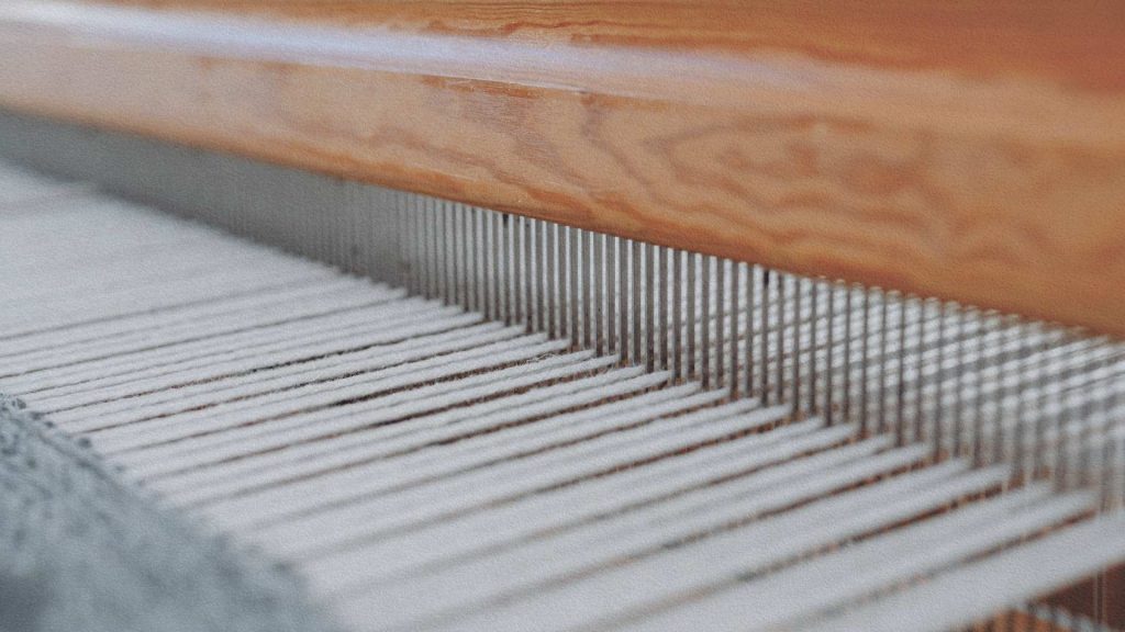 Fils tendus sur un métier à tisser industriel illustrant la mécanisation de l'industrie textile