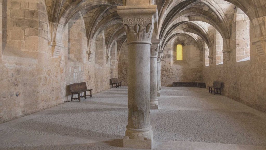 Intérieur d'un monastère médiéval aux voûtes de pierre évoquant l'atmosphère des abbayes et des bibliothèques du Moyen Âge.
