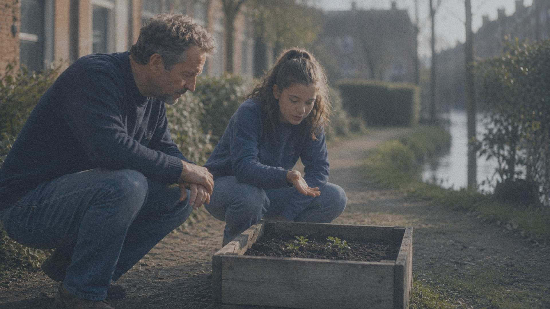 Un père et sa fille observent un petit jardin partagé avant de déplacer ensemble un bac de culture dans un quartier résidentiel des Pays-Bas.