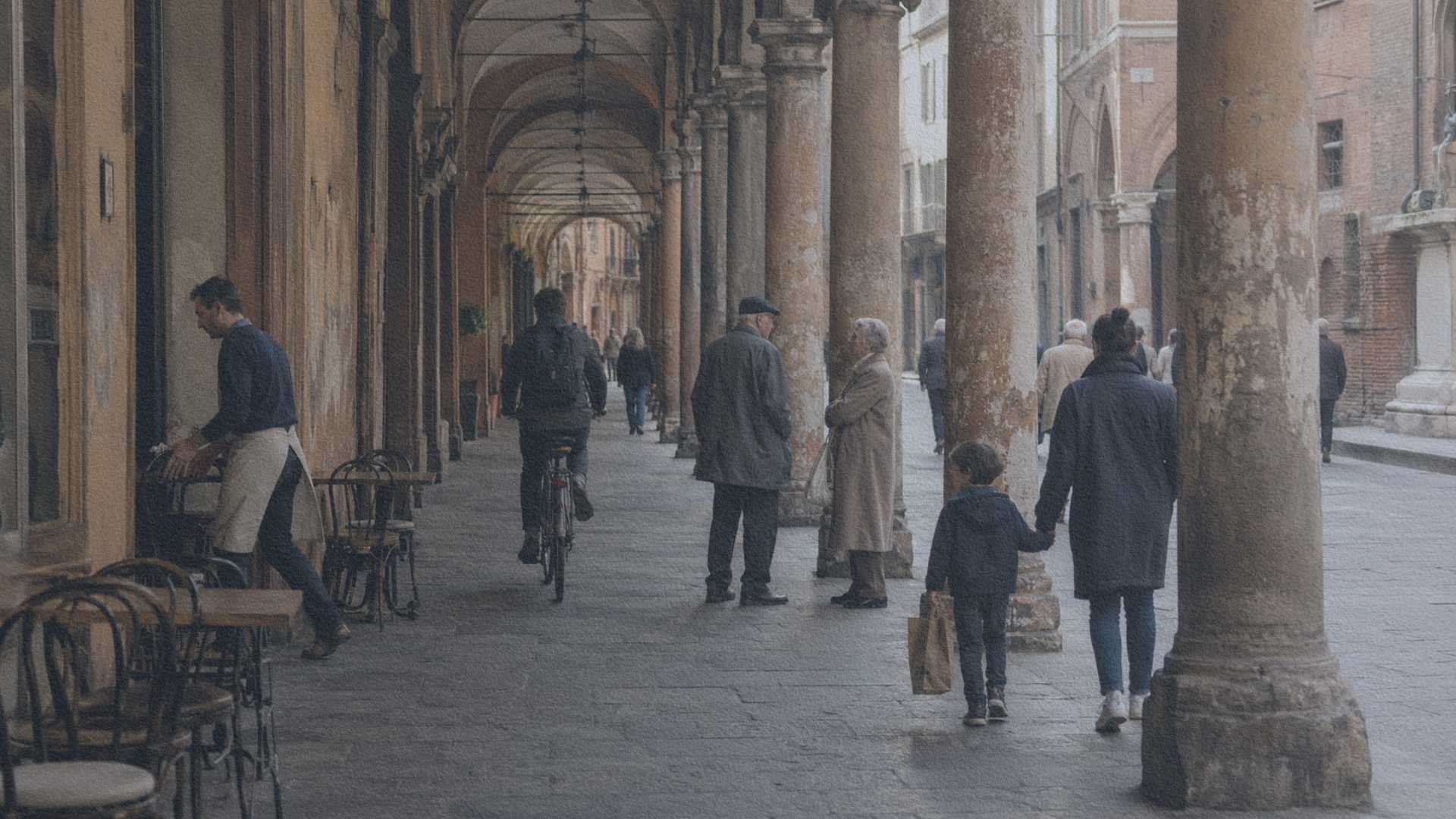 Habitants circulant sous les arcades médiévales de Bologne, où le patrimoine historique reste pleinement intégré à la vie quotidienne.