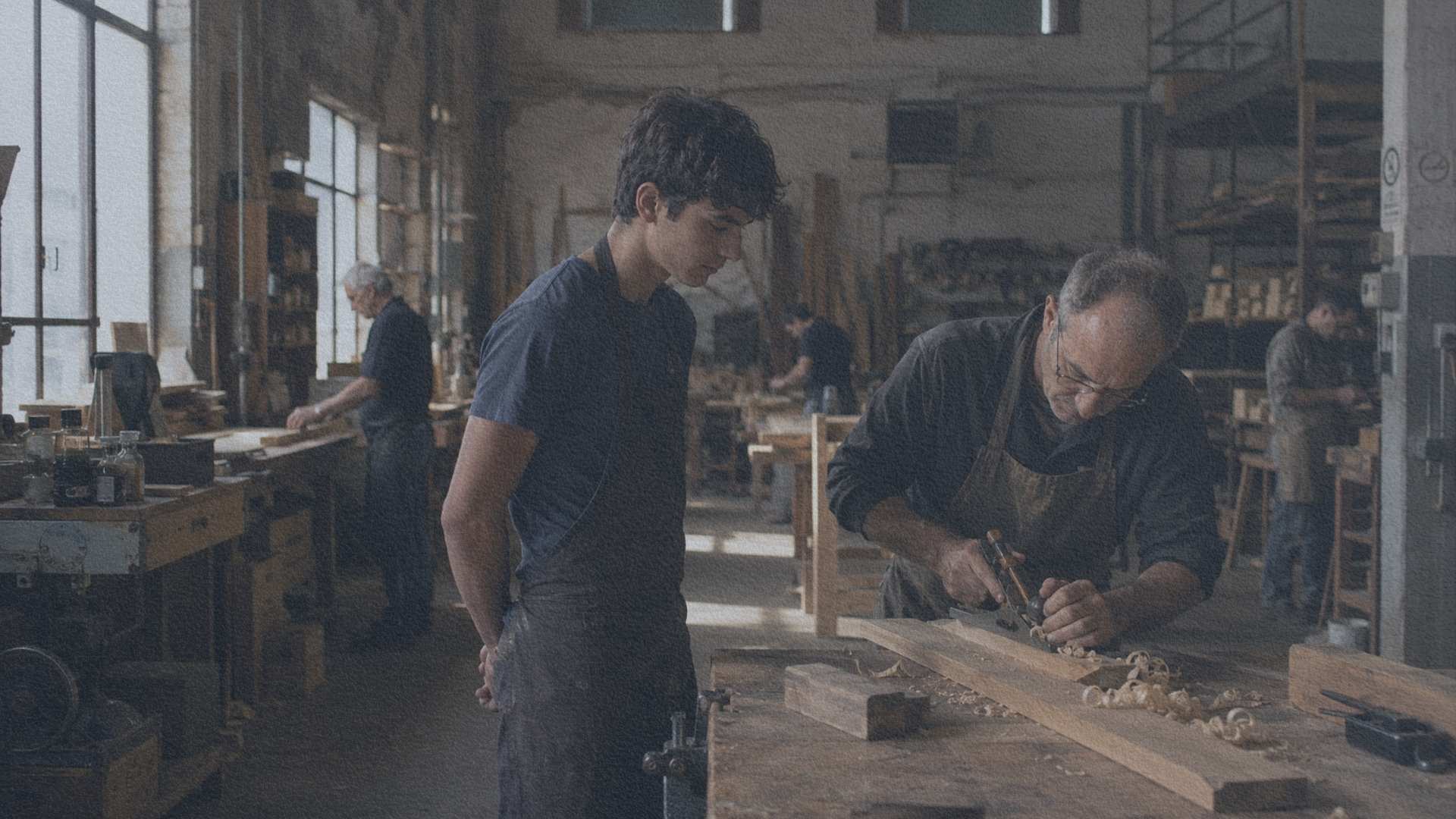 eune apprenti observant un artisan expérimenté au début d'une journée dans un atelier italien.