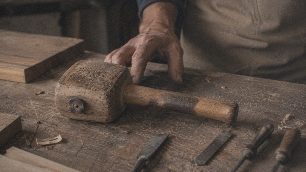 Gros plan sur un maillet en bois marqué par des années d'utilisation dans un atelier artisanal italien.