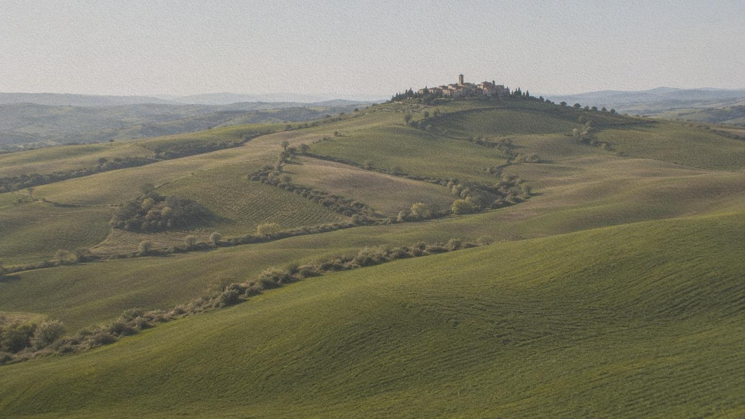 Paysage de Toscane montrant collines, villages et terres agricoles organisées.