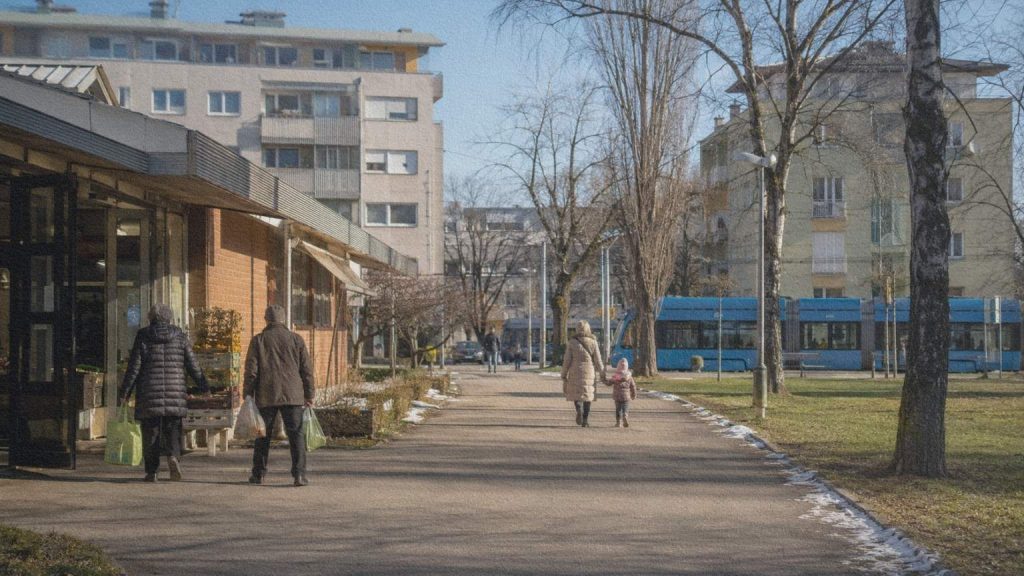 Habitants quittant le marché d’Utrina parmi les logements et les espaces verts de Novi Zagreb en hiver.