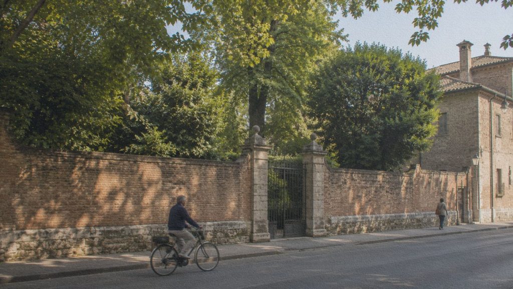 Mur de briques et végétation dans une rue de Ferrare, évoquant la géographie du jardin fictif imaginé par Giorgio Bassani.
