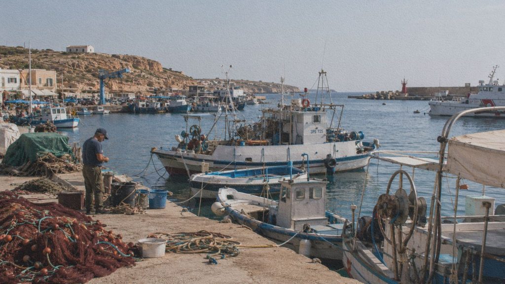 Port de Lampedusa avec bateaux de pêche et activité maritime, lieu central des récits de secours dans La Loi de la mer.