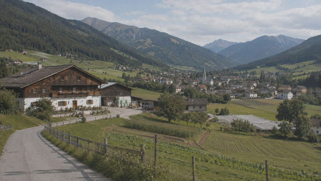 Vallée rurale habitée du Haut-Adige avec ferme et prairies, évoquant le monde familial de Gerda dans Eva dort.