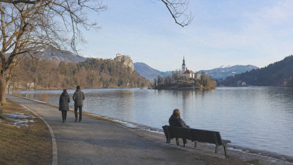 Promeneurs au bord du lac de Bled face à l’île pendant un après-midi d’hiver.