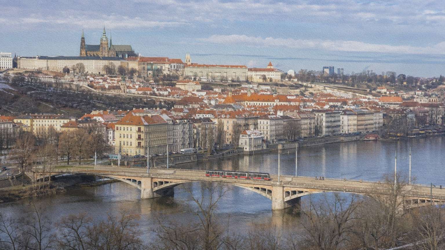 Vue hivernale de Prague autour de la Vltava, avec un tramway traversant le fleuve et les quartiers montant vers le château.
